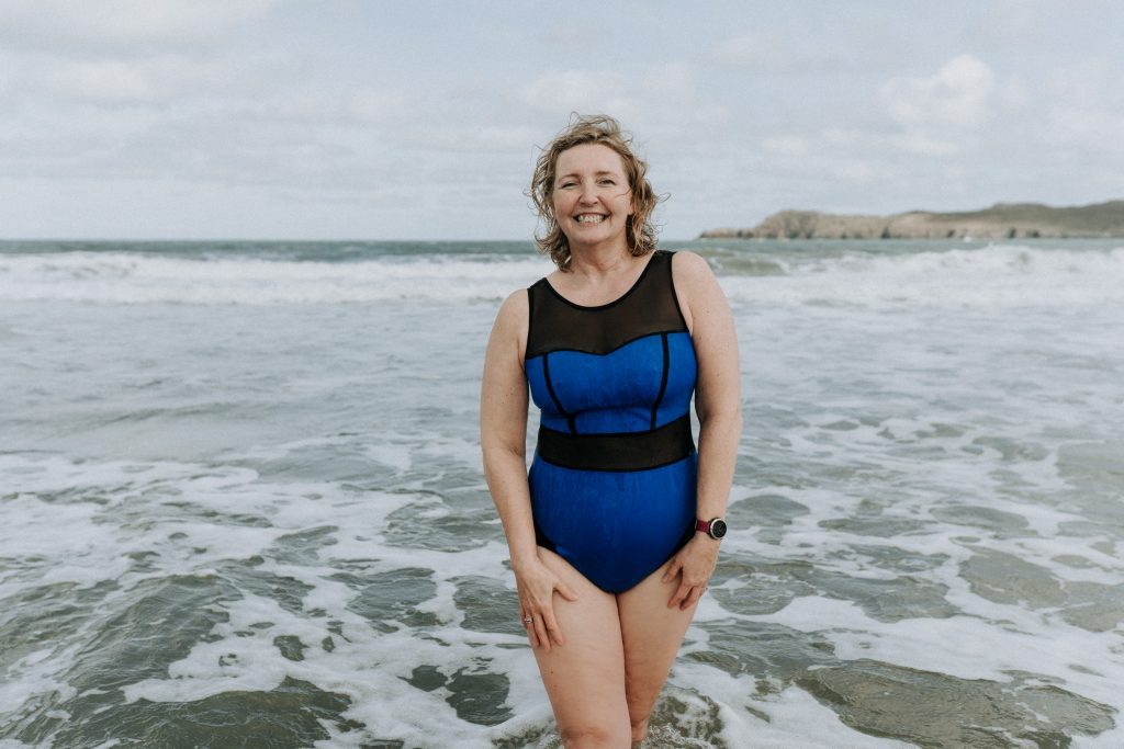 Model wearing blue swim costume standing in sea