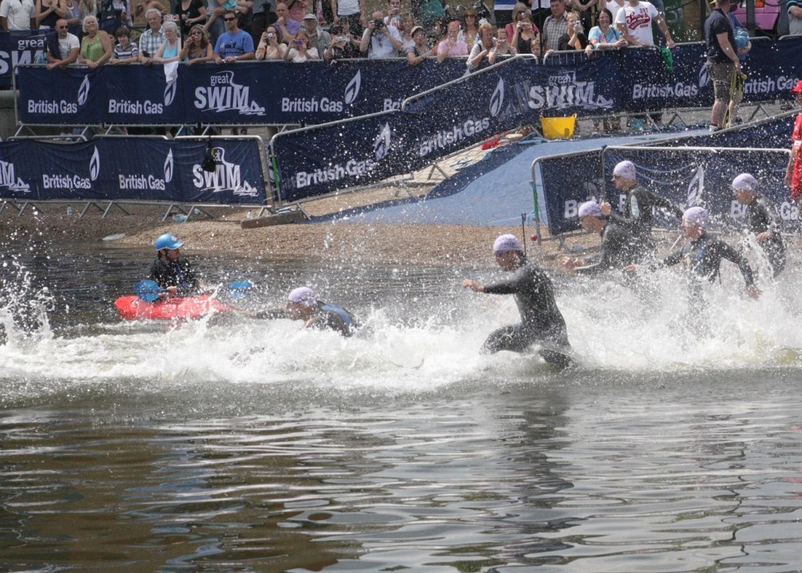 Swimmers in wetsuits running into the water at the start of the Great London Swim 2011