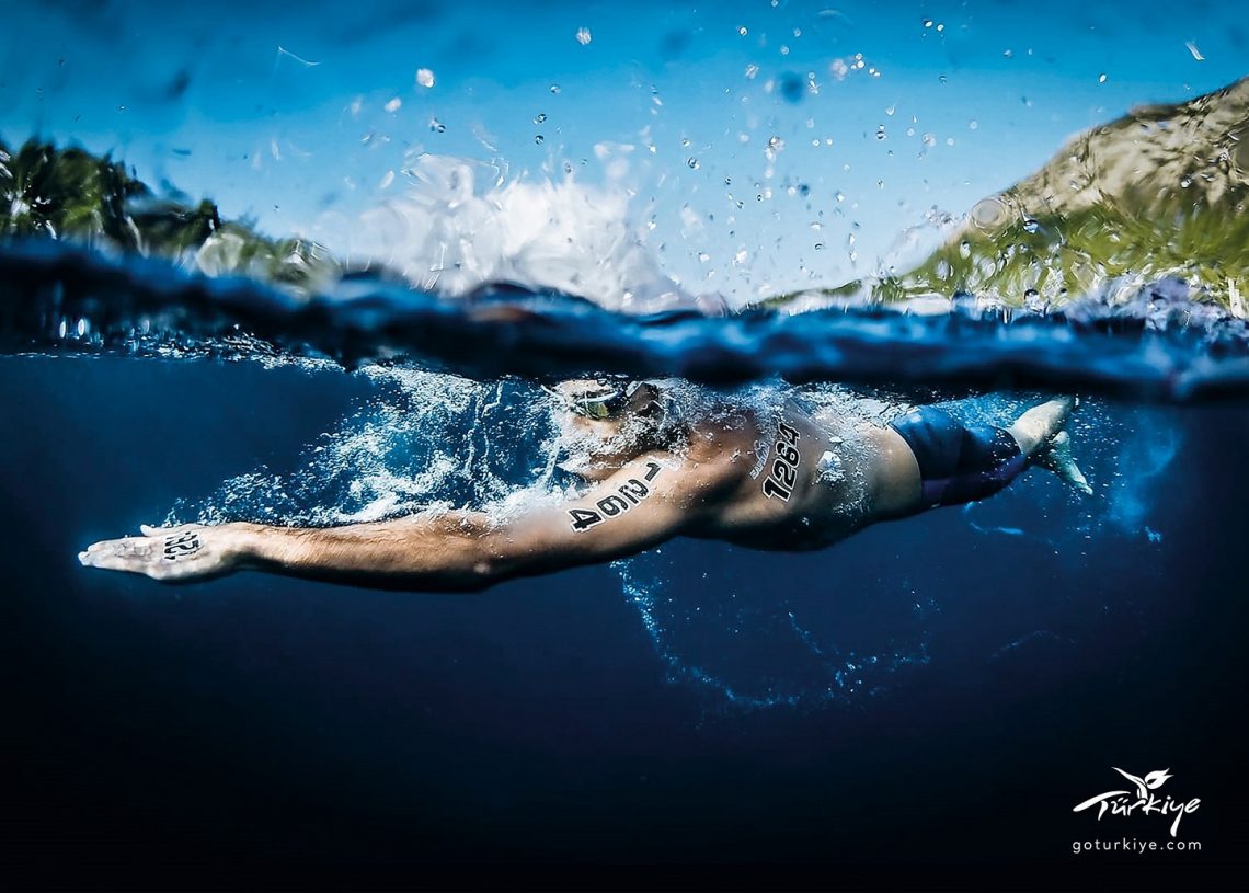 A swimmer in the sea, split screen image with half above and half below the water.