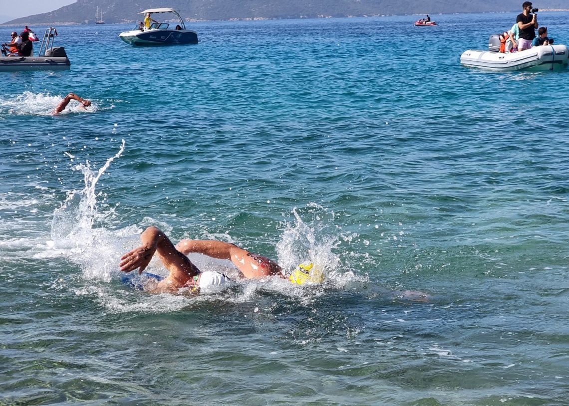 Two swimmers, shoulder to shoulder, finishing a race in the sea, heading towards the camera.