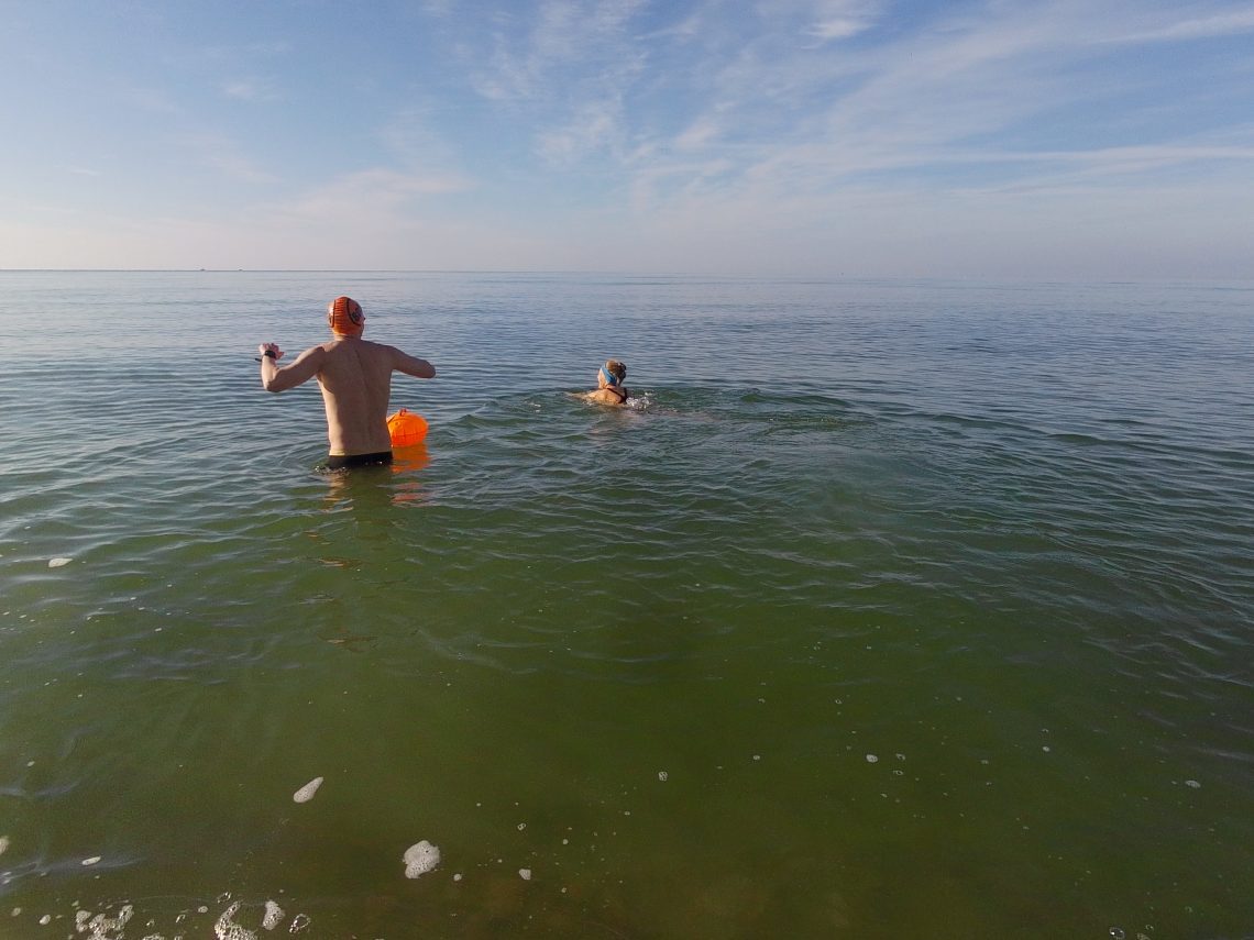 Two swimmers wading into the sea
