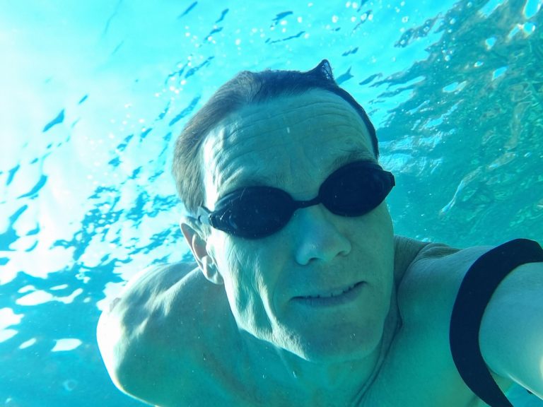 A selfie of a Simon Griffiths underwater with goggles, no cap, looking towards the camera