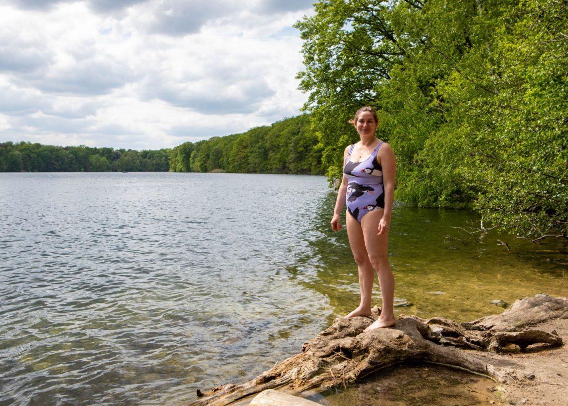 A woman in a swimming costume standing next to a lake